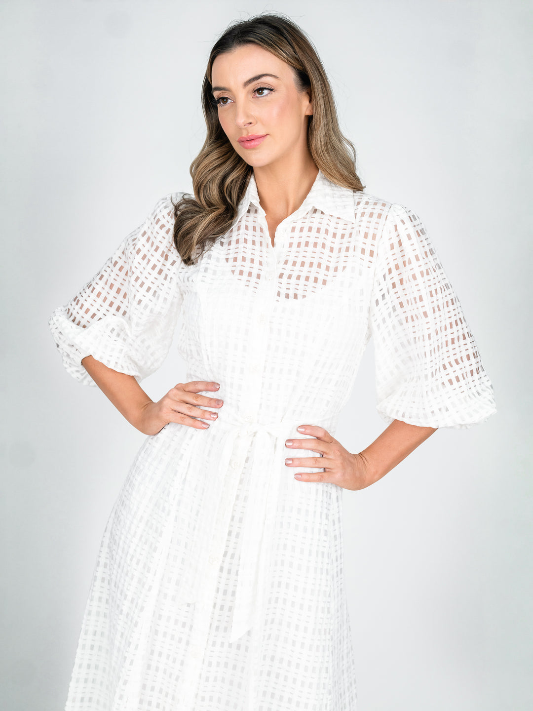 Close up women's sheer white shirt dress with blouson 3/4 length sleeves and a-line midi length skirt